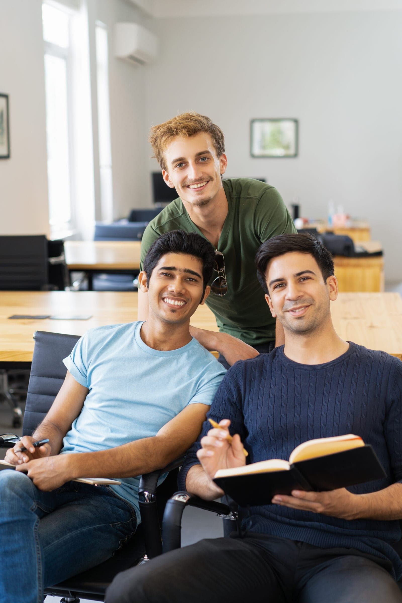 Three university students smiling in campus classroom